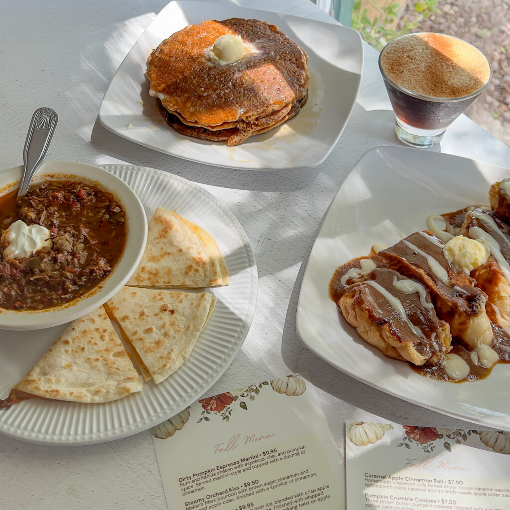 A variety of classic American dishes including a burger, chili with tortilla chips, and a dessert with caramel and whipped cream, served at The Gilbert House Restaurant.