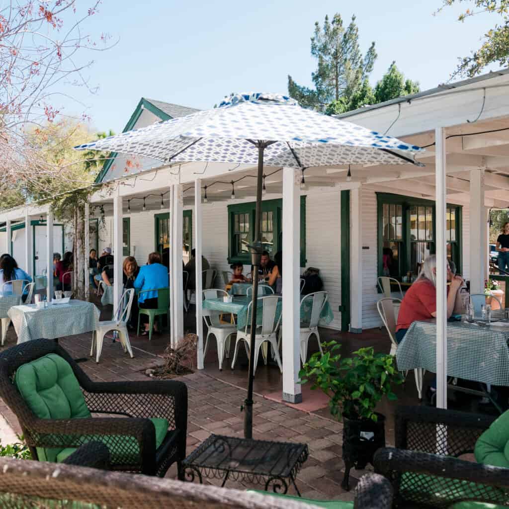 Spacious outdoor patio featuring tables with checkered tablecloths, umbrellas, and ample seating, ideal for private parties and special events at Gilbert House Restaurant.
